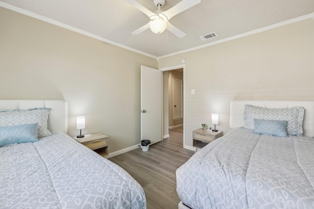 bedroom featuring ceiling fan, baseboards, wood finished floors, visible vents, and ornamental molding