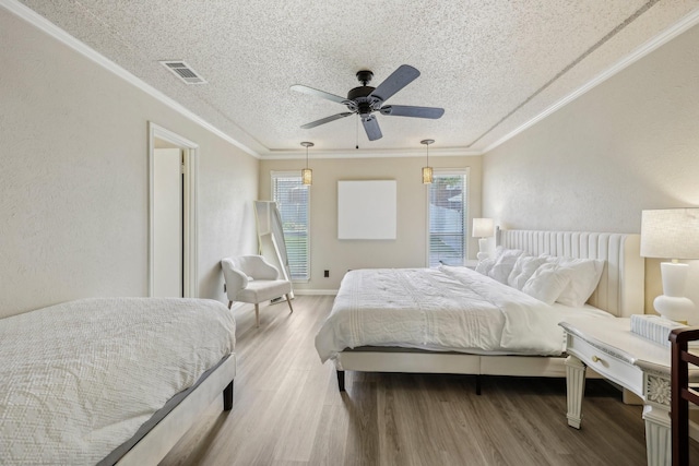 bedroom with crown molding, visible vents, wood finished floors, ceiling fan, and a textured ceiling