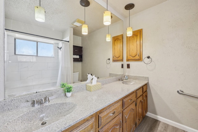 bathroom featuring baseboards, a sink, wood finished floors, and double vanity