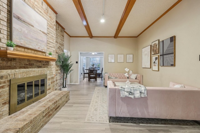 living room with a brick fireplace, beamed ceiling, ornamental molding, and wood finished floors