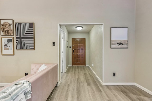 corridor featuring light wood-style floors and baseboards