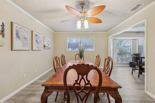 dining room with wood finished floors, a ceiling fan, a textured ceiling, and visible vents