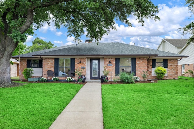 ranch-style house with brick siding, a front lawn, and roof with shingles