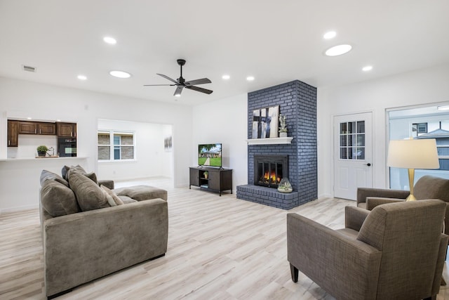 living room featuring ceiling fan, visible vents, a fireplace, light wood-style floors, and recessed lighting