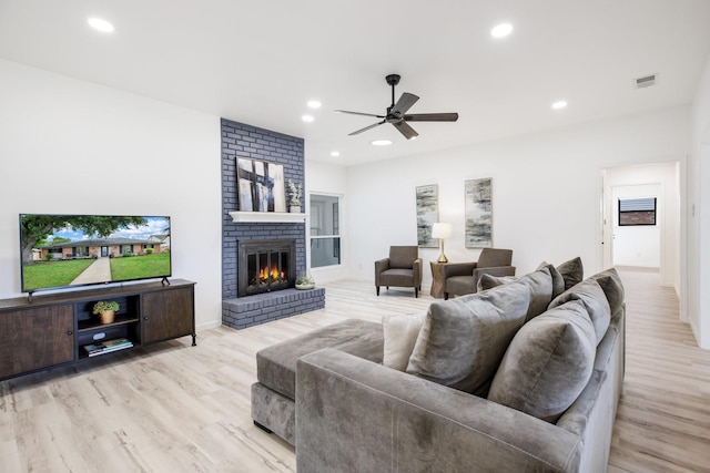 living room with a ceiling fan, visible vents, a fireplace, wood finished floors, and recessed lighting