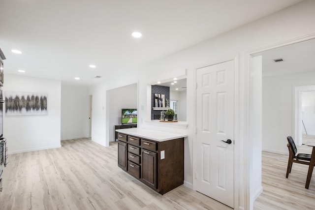 kitchen featuring light wood-type flooring, light countertops, dark brown cabinetry, and visible vents
