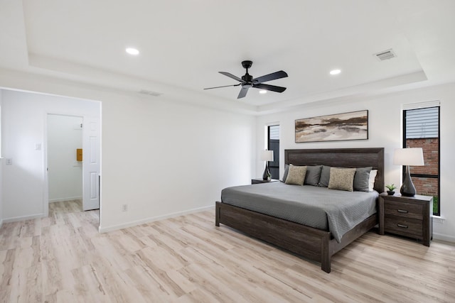 bedroom with visible vents, a raised ceiling, and light wood-style floors