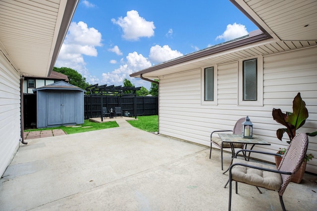 view of patio featuring fence, a storage unit, and an outbuilding