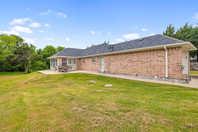 back of house with brick siding, a lawn, and a patio