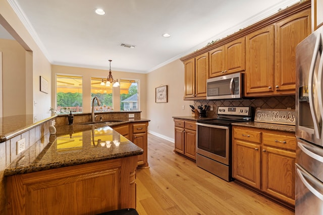 kitchen featuring ornamental molding, brown cabinets, tasteful backsplash, a sink, and appliances with stainless steel finishes