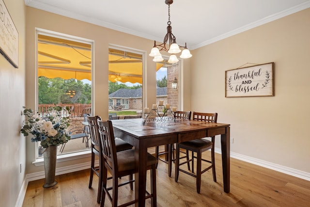 dining area with baseboards, an inviting chandelier, ornamental molding, and light wood-style floors