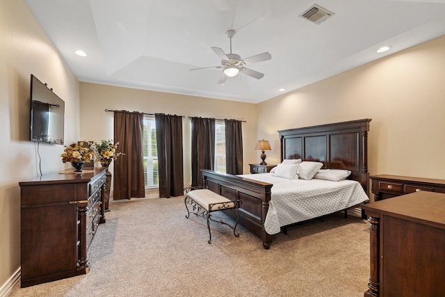bedroom featuring visible vents, recessed lighting, a tray ceiling, and light carpet