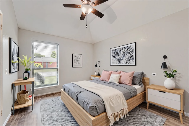 bedroom with baseboards, a ceiling fan, wood finished floors, and lofted ceiling