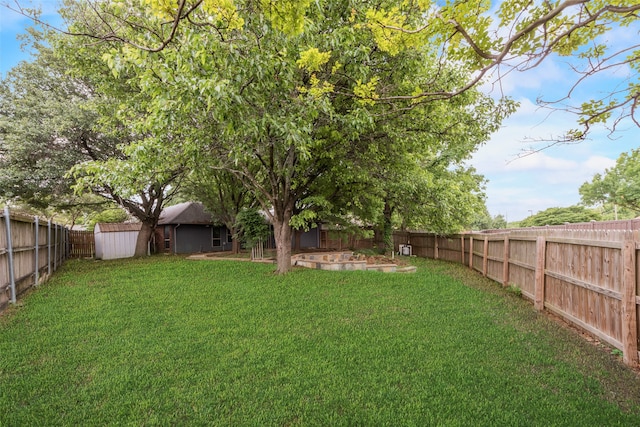 view of yard featuring an outbuilding, a fenced backyard, and a storage unit