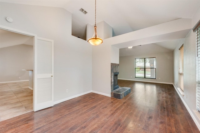 unfurnished living room featuring a tiled fireplace, vaulted ceiling, and visible vents
