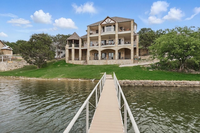 dock area with a water view, a yard, and a balcony