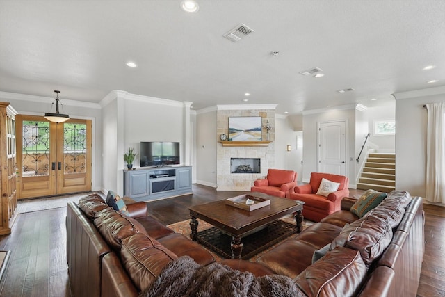 living room featuring a stone fireplace, stairs, recessed lighting, dark wood-type flooring, and visible vents