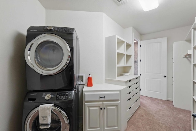 washroom with cabinet space, stacked washer / drying machine, light colored carpet, and visible vents
