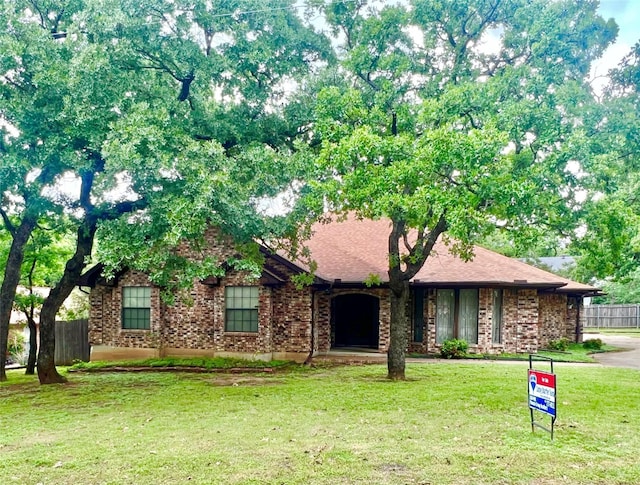 ranch-style home with fence, brick siding, and a front yard