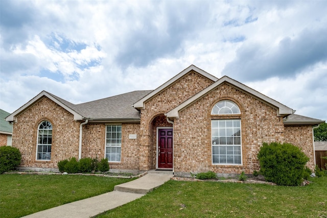 ranch-style house featuring brick siding, a shingled roof, and a front yard