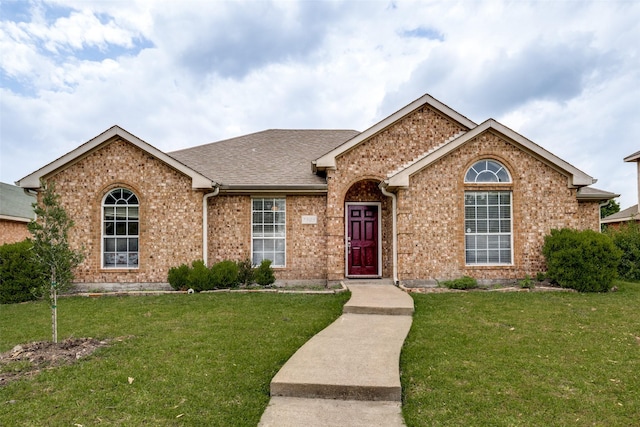 ranch-style house featuring brick siding, a shingled roof, and a front yard