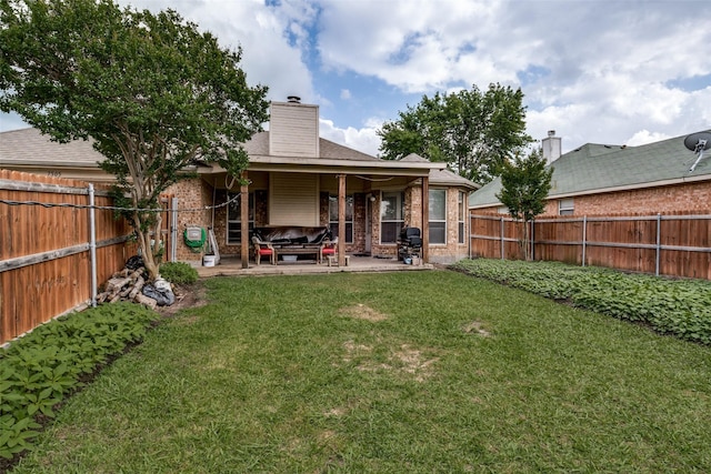 back of house featuring a lawn, brick siding, a patio, and a fenced backyard
