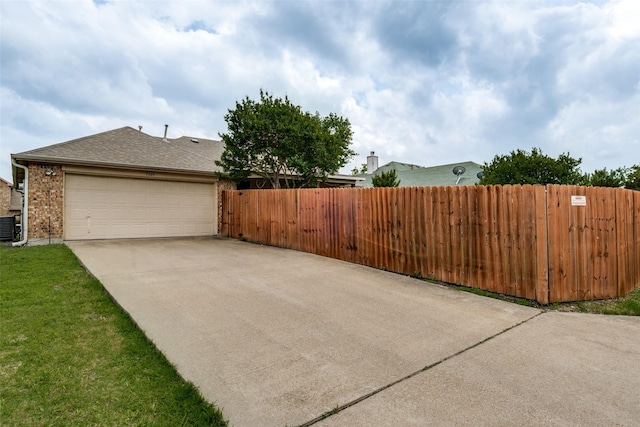 exterior space featuring driveway, brick siding, fence, an attached garage, and a shingled roof