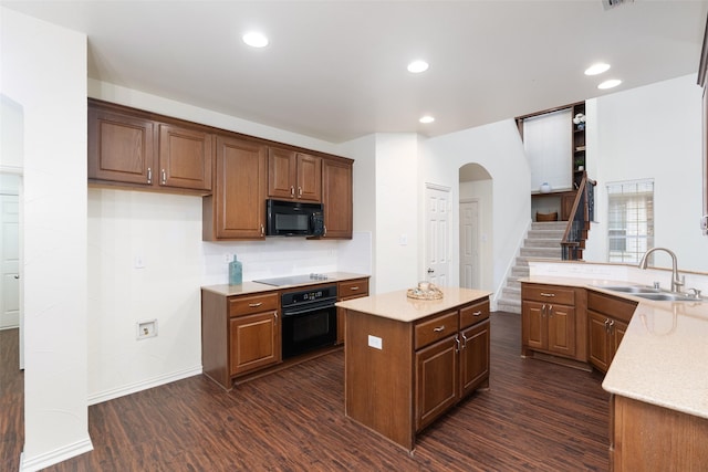 kitchen with a kitchen island, arched walkways, a sink, dark wood finished floors, and black appliances