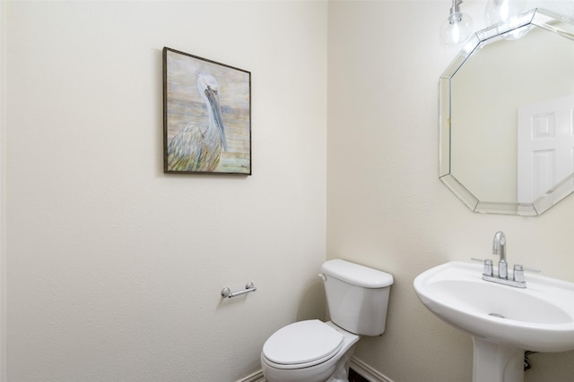 half bathroom featuring baseboards, a sink, and toilet