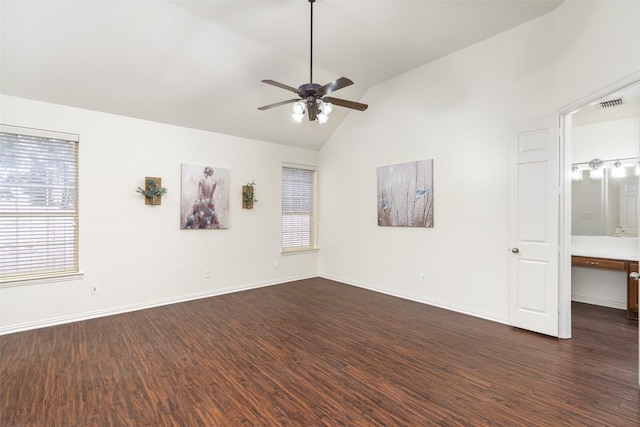 empty room featuring visible vents, a healthy amount of sunlight, ceiling fan, dark wood finished floors, and vaulted ceiling