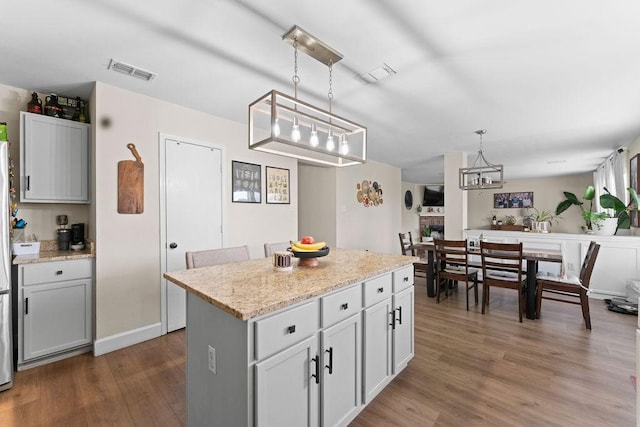 300 Aspenwood Trl, Forney, TX 75126 - kitchen with visible vents, wood finished floors, a kitchen island, a notable chandelier, and hanging light fixtures