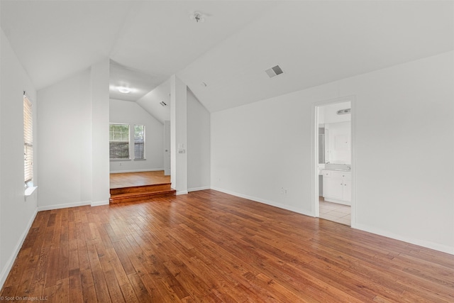 interior space featuring baseboards, lofted ceiling, visible vents, and hardwood / wood-style floors