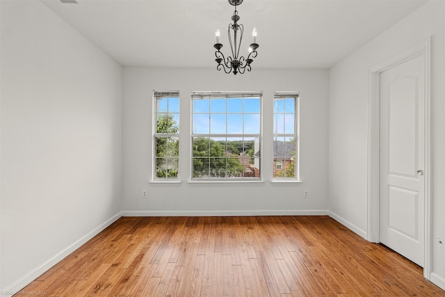 unfurnished dining area with an inviting chandelier, light wood-style flooring, baseboards, and a wealth of natural light