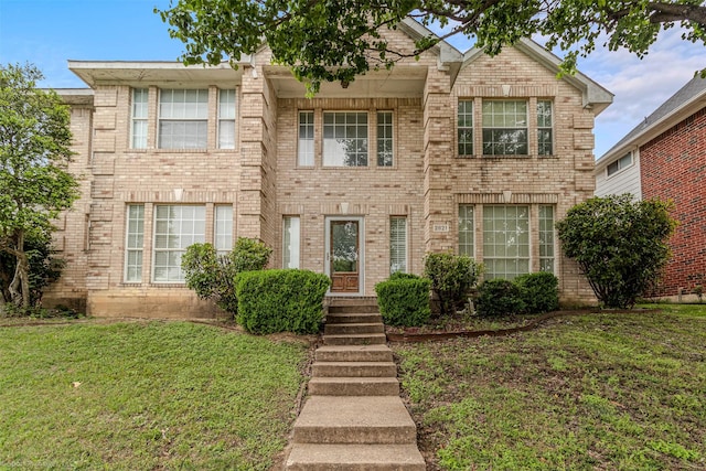view of front facade with brick siding and a front yard