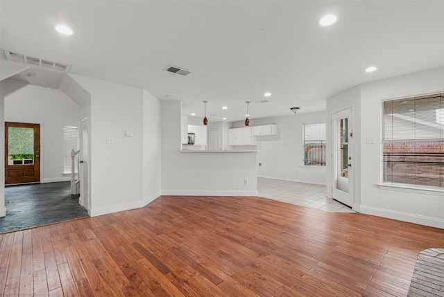unfurnished living room featuring baseboards, visible vents, light wood finished floors, and a wealth of natural light