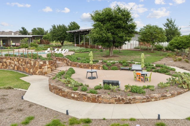 view of community featuring fence, a pool, and a patio area