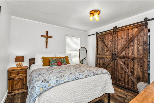 bedroom with crown molding, baseboards, a barn door, and wood finished floors