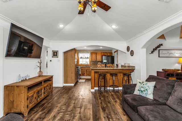 living area with arched walkways, baseboards, and dark wood-type flooring