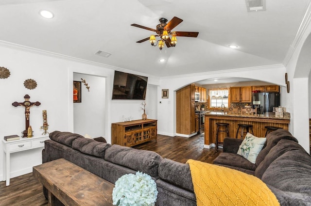 living area with visible vents, arched walkways, a ceiling fan, and crown molding