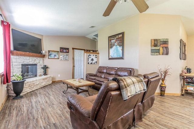 living area with ceiling fan, a fireplace, baseboards, wood finished floors, and vaulted ceiling