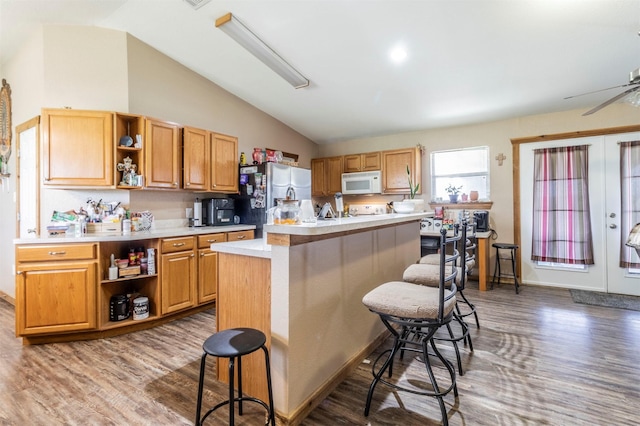 kitchen with open shelves, wood finished floors, white microwave, freestanding refrigerator, and lofted ceiling