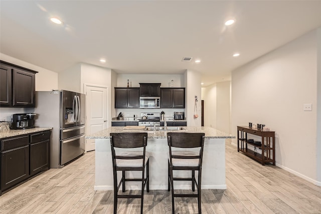 kitchen with stainless steel appliances, a sink, visible vents, and light wood-style flooring