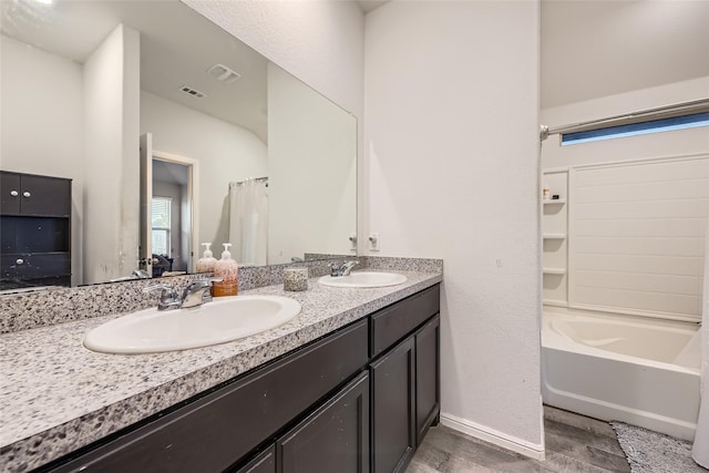 bathroom featuring double vanity, visible vents, a sink, and wood finished floors