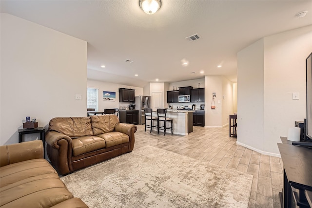 living area featuring visible vents, recessed lighting, light wood-style floors, and baseboards