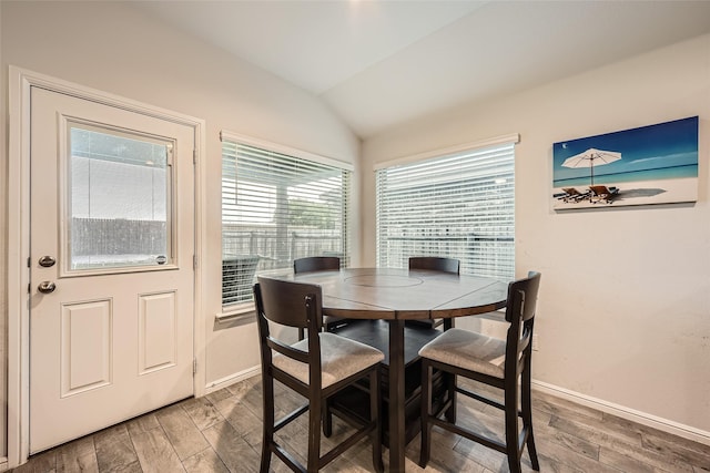 dining room featuring baseboards, wood finished floors, and vaulted ceiling