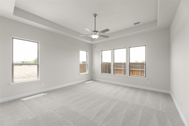 spare room featuring a raised ceiling, baseboards, ceiling fan, and light colored carpet
