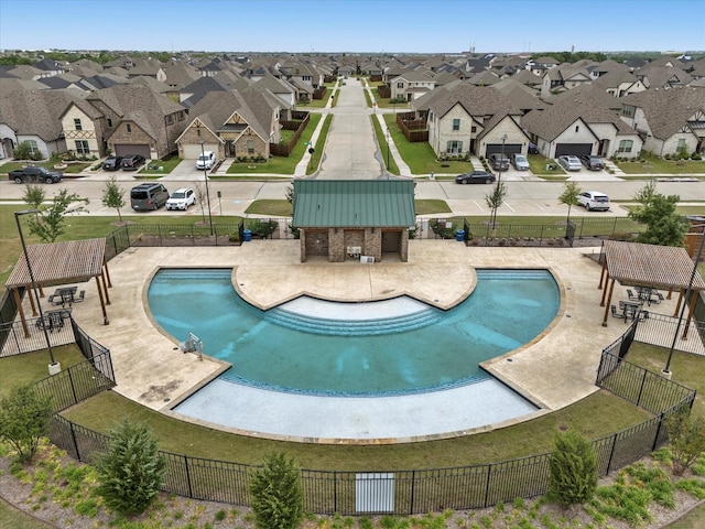 pool with a residential view, fence, and a yard
