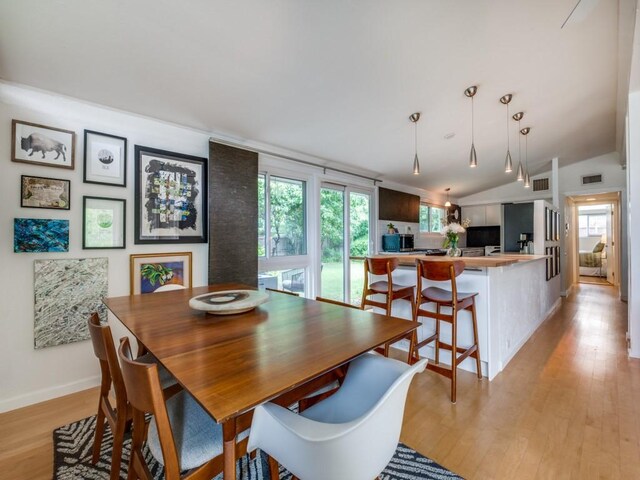 dining room with baseboards, vaulted ceiling, light wood-style flooring, and visible vents