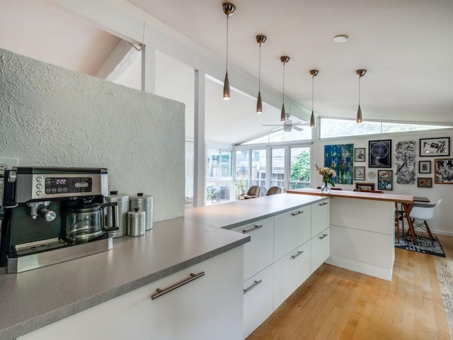 kitchen with ceiling fan, vaulted ceiling with beams, white cabinetry, light wood finished floors, and hanging light fixtures