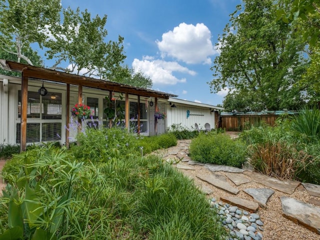 rear view of property featuring board and batten siding and fence